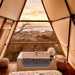 A tent with a bathtub, a view of the landscape, and a window. - One-of-a-Kind Cliffside Glamping Experience with Sky Views in Cottonwood Shores, Texas (Cottonwood Shores)