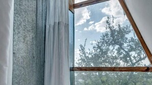 Una habitación con un ventanal grande, vigas de madera y una cortina.