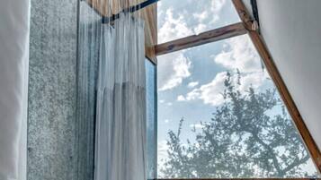 A room with a large window, wooden beams, and a curtain.