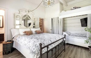 Een slaapkamer met een bed, nachtkastje, spiegel, garderobe, inbouwbank en hanglamp.