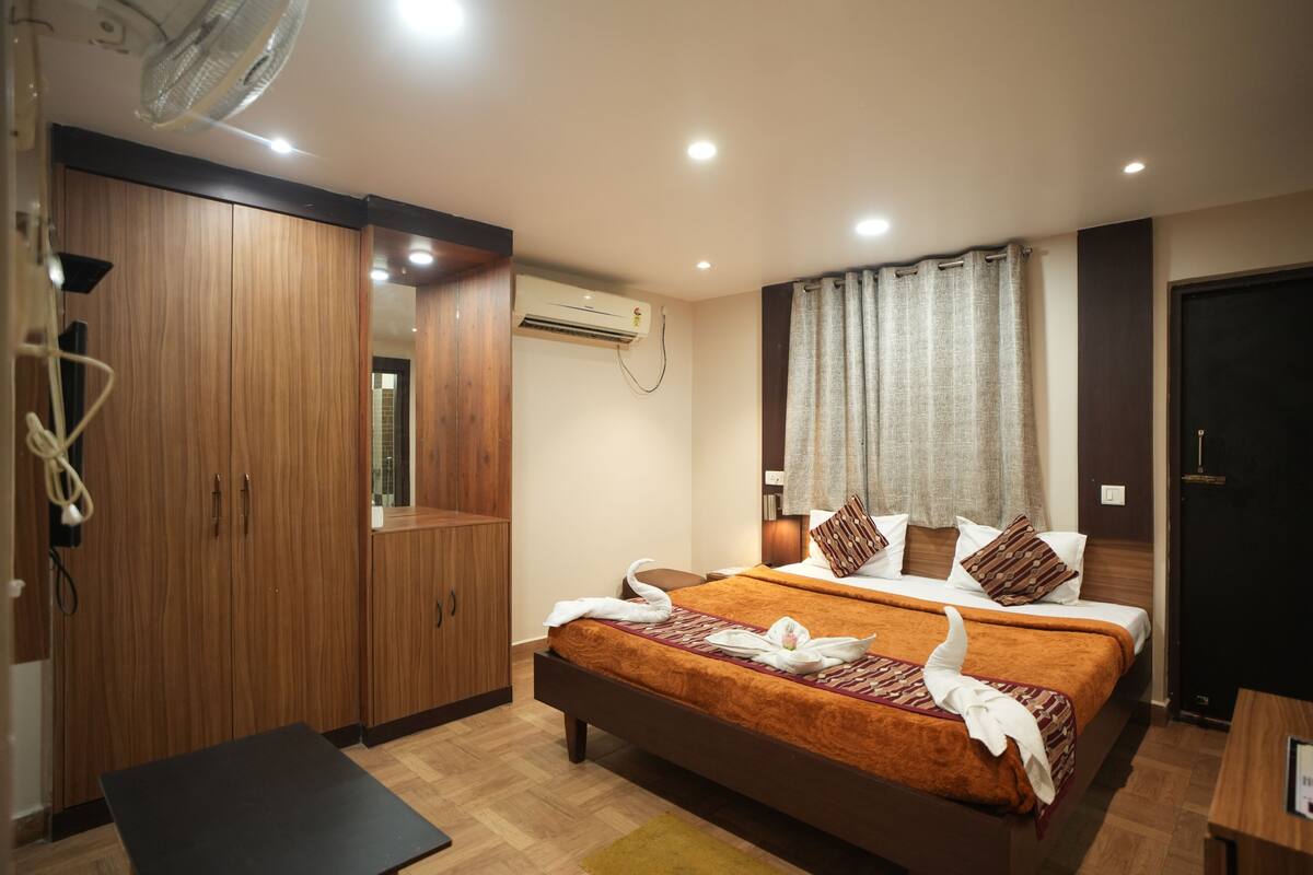 Habitación de hotel con cama, armario de madera, equipo de aire acondicionado y escritorio.