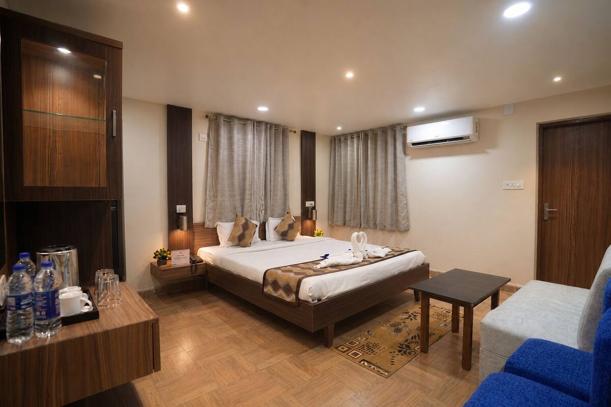 Habitación de hotel con cama, mesita de noche y escritorio con botellas de agua.