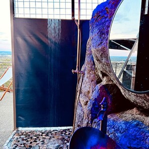A bathroom with a large mirror, a shower, and a view of the landscape.