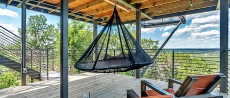 Una terraza de madera con una hamaca colgante y vistas al paisaje.