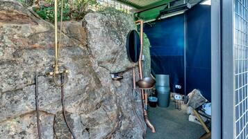 A rustic interior with a stone wall, metal fixtures, and a blue tarp-covered area.