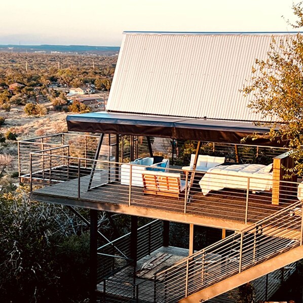 Una terraza moderna al aire libre con mobiliario y una zona cubierta, con vistas a un paisaje desértico.