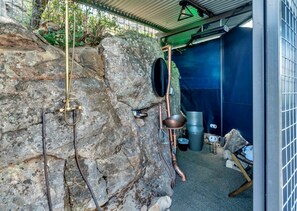 A rustic interior with a stone wall, metal fixtures, and a blue tarp-covered area.