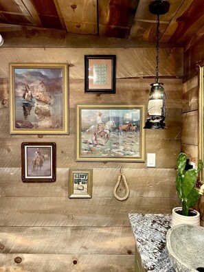 Eine rustikale Holzwand mit gerahmten Kunstwerken, einem hängenden Laternen und einem Topfpflanzen.