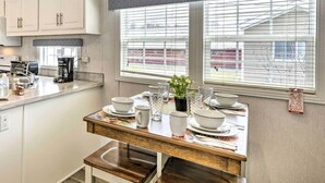 Een keuken met een eettafel voor vier personen, een koffiezetapparaat en een raam met jaloezieën.
