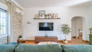 Una sala de estar con televisor, sofá y objetos decorativos.