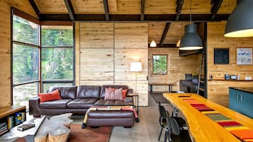 A cozy cabin interior with a wooden interior, a sofa, a dining table, and a bar area.