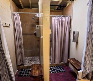 A small, enclosed shower area with a showerhead, a bench, and a number sign indicating room 4. - Vintage Airstream Stay Beneath Oaks & Starry Skies in Pauma Valley, California (Pauma Valley)