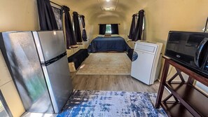 A compact RV interior with a kitchenette, a bed, and a small bathroom. - Vintage Airstream Stay Beneath Oaks & Starry Skies in Pauma Valley, California (Pauma Valley)