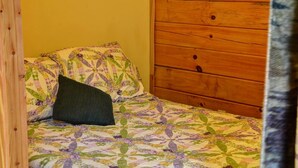 Una cama pequeña con una colcha estampada con motivos florales y una almohada oscura.