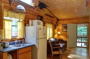 A cabin interior with a kitchen, dining area, and a cozy seating space. - Cozy Log Cabin for Getaway in the Mountains near Cherokee, North Carolina (Cherokee)