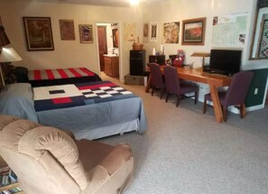 A room with a bed, a desk, a chair, and a television.