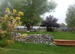 A garden with a stone wall, a tree, and a wooden bench.