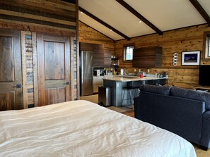 A modern kitchen with stainless steel appliances, a central island, and a dining area with a sofa. - Luxury Flathead Lake Cabin with Stunning Views (Somers)