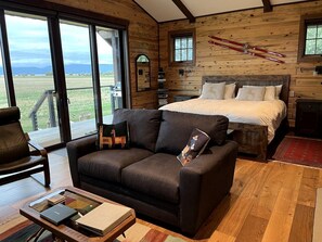 Ein gemütliches Blockhausschlafzimmer mit einem großen Bett, einer Couch und einem Essbereich.