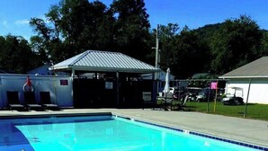 Une piscine dotée d’une zone couverte, d’un espace clos par une clôture et d’un bâtiment en arrière-plan.