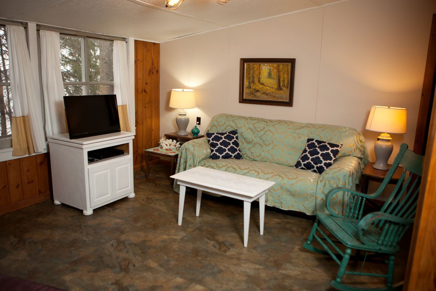 Una sala de estar acogedora con televisor, sofá, mesa de centro y sillón.