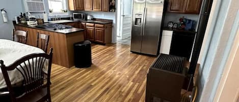 A kitchen with wooden cabinets, a central island, a ceiling fan, and a refrigerator.