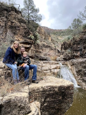 Una familia sentada sobre una formación rocosa, con una cascada al fondo.