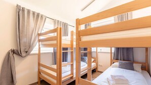 Una habitación con literas, una ventana con cortinas y una cama con almohadas.