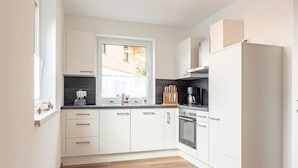 Una cocina moderna con armarios blancos, una ventana y un horno empotrado.