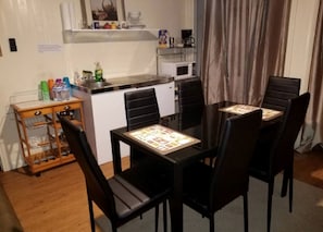 Eine kompakte Küche mit Mikrowelle, einem kleinen Esstisch mit Stühlen und einer Holzseitenschrank mit Stauraum.