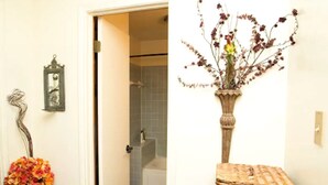 Un baño con ducha, espejo y puerta que da a otra habitación.