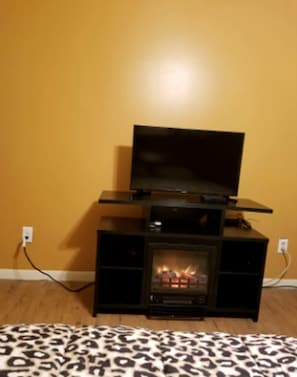 A room with a fireplace, a television on a stand, and a leopard print rug. - Unique Duplex Rental by Reese Creek for a Weekend Getaway in Texas (Killeen)