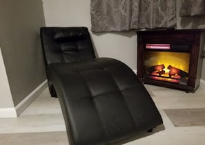 A room with a black leather chair, a small wooden cabinet with a fireplace, and a patterned curtain. - Unique Duplex Rental by Reese Creek for a Weekend Getaway in Texas (Killeen)