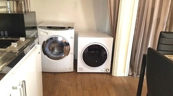 Une cuisine compacte équipée d’un four à micro-ondes, d’un lave-linge et d’un sèche-linge.