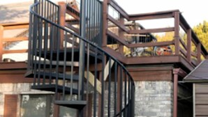 A modern building with a spiral staircase, a brick wall, and a metal fence.