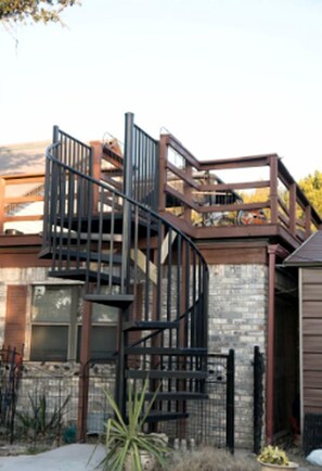 A modern building with a spiral staircase, a brick wall, and a metal fence.
