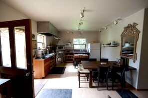 A compact kitchen with a dining area, wooden cabinets, a microwave, and a refrigerator.