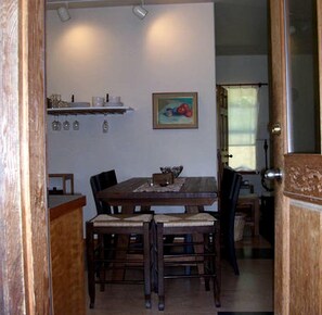 A dining area with a wooden table, chairs, and a painting on the wall.