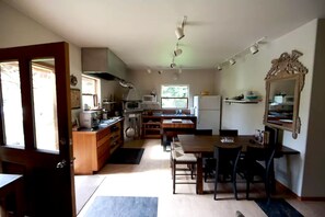 Een kleine keuken met een eethoek, houten kastjes, een magnetron en een koelkast.
