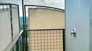 Een omheind buitengebied met kunstgras, een metalen poort en een gebouw met een grijze gevel.