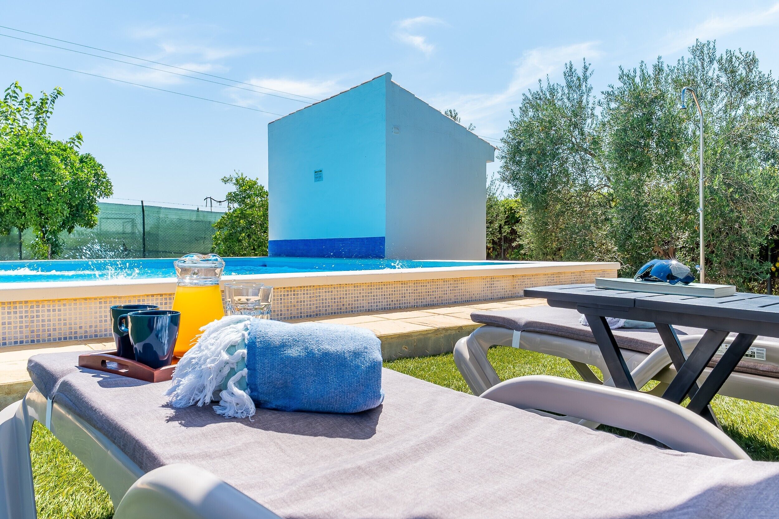 Un espace aménagé au bord de la piscine, avec des chaises longues, une table et une boisson.