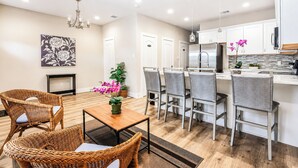 Una cucina moderna con mobili bianchi, una zona pranzo con sedie in vimini e una ventola a soffitto.