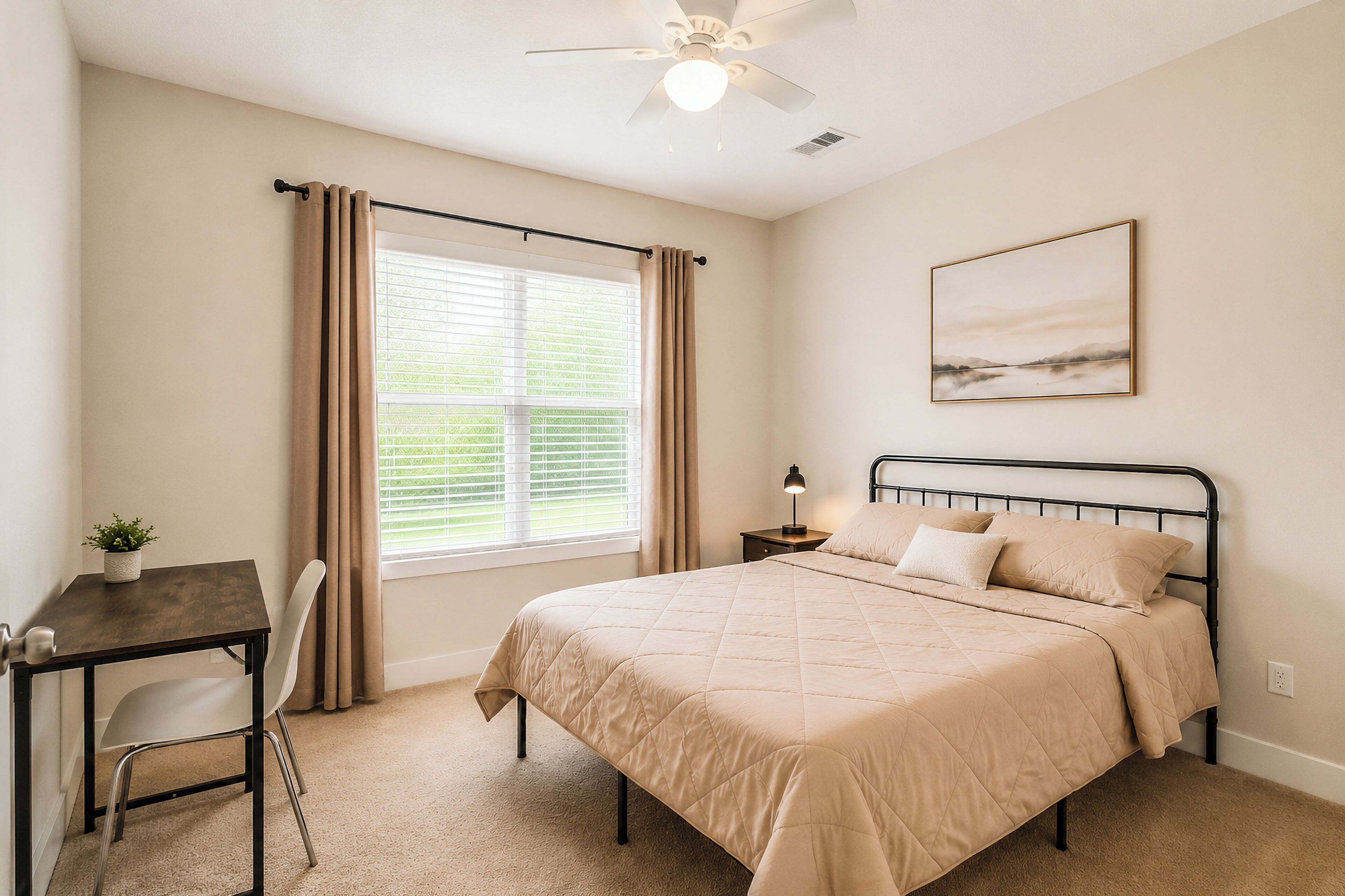A bedroom with a bed, a desk, a chair, a ceiling fan, a window with curtains, and a wall-mounted picture.