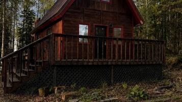 A wooden cabin with a balcony, surrounded by trees.