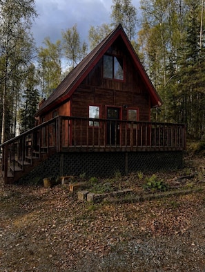 Puurakenteinen mökki, jossa on parveke, ja sen ympärillä on puita.