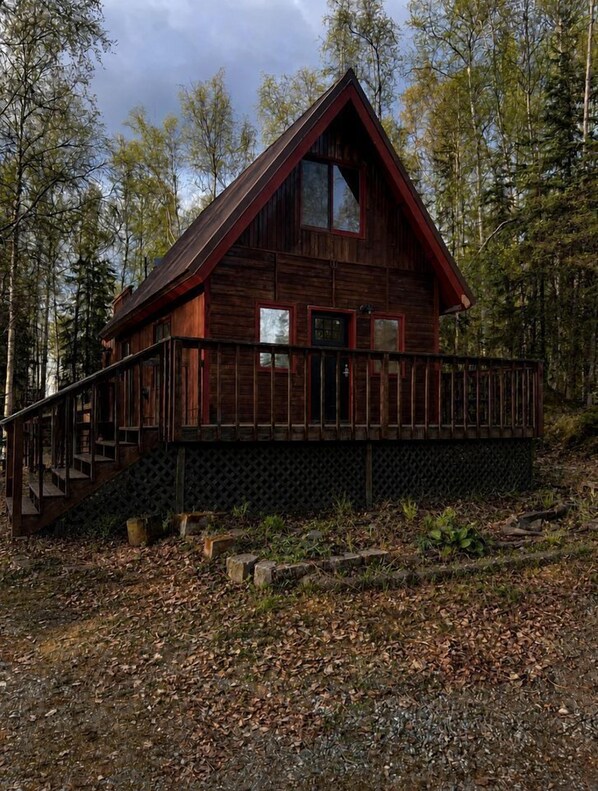 Une cabane en bois dotée d’un balcon, entourée d’arbres.