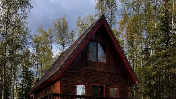 Eine Holzhütte mit Balkon, umgeben von Bäumen.
