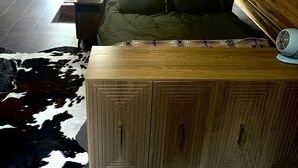 Une chambre confortable située dans les combles, avec un lit, une armoire en bois, un ventilateur et un tapis en peau de vache.