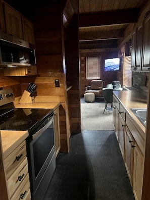 Una cocina pequeña con armarios de madera, una estufa y un microondas.