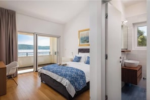 Une chambre avec un lit, un bureau, une salle de bain avec un lavabo et une vue sur l’extérieur.